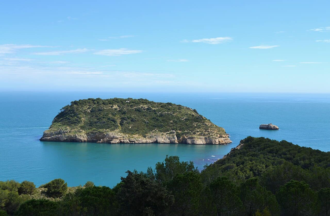 La isla del Portitxol, cubierta de pinos, frente a la costa de Xàbia